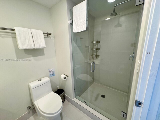 bathroom with a shower with door, tile floors, and toilet