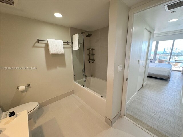 bathroom featuring tiled shower / bath combo, toilet, and tile flooring