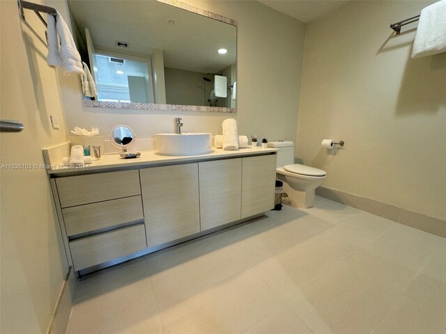 bathroom with toilet, vanity, and tile flooring