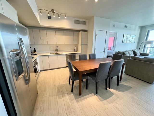 dining area with light hardwood / wood-style floors, sink, and track lighting