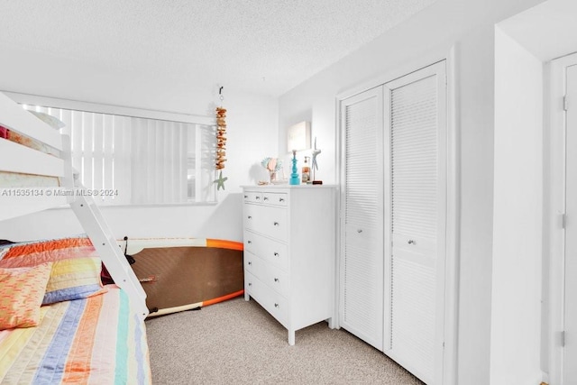 bedroom featuring a textured ceiling, light colored carpet, and a closet