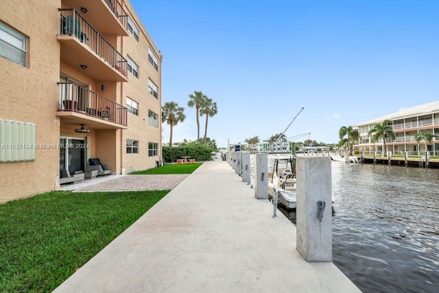 view of dock with a water view and a yard