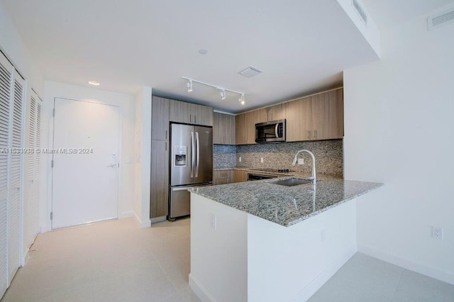 kitchen with sink, light stone counters, appliances with stainless steel finishes, backsplash, and light tile flooring