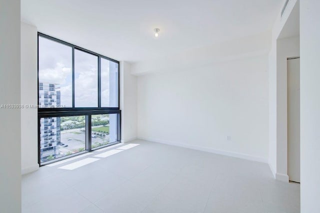 empty room featuring light tile flooring and expansive windows