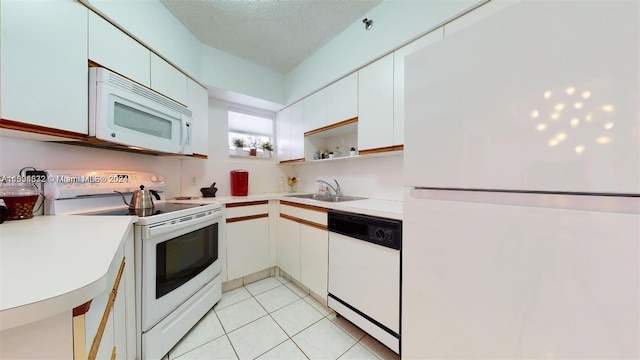 kitchen with light tile flooring, a textured ceiling, white appliances, white cabinets, and sink