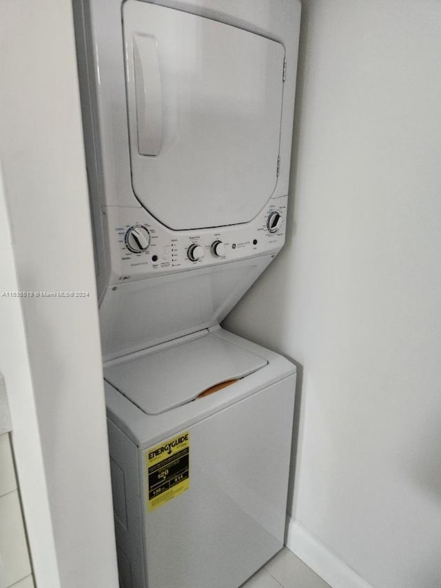 laundry area with stacked washer and clothes dryer and light tile flooring