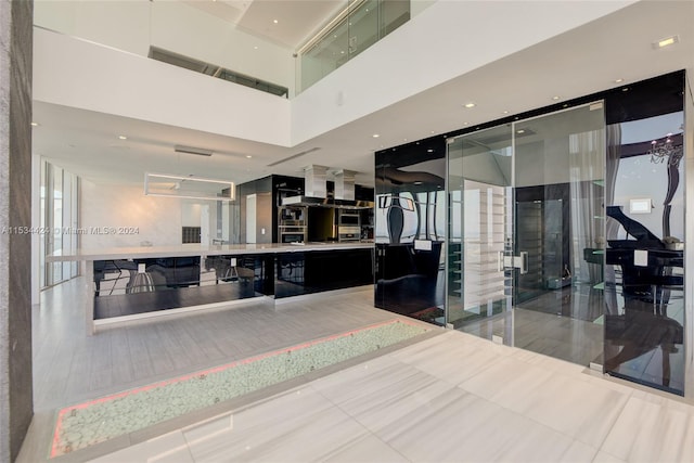 kitchen featuring wall chimney range hood, light tile floors, and oven