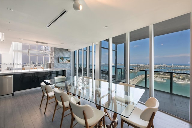 dining space featuring indoor bar, a water view, expansive windows, and light hardwood / wood-style flooring