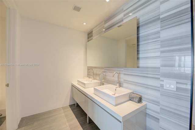 bathroom featuring backsplash, oversized vanity, tile floors, and dual sinks