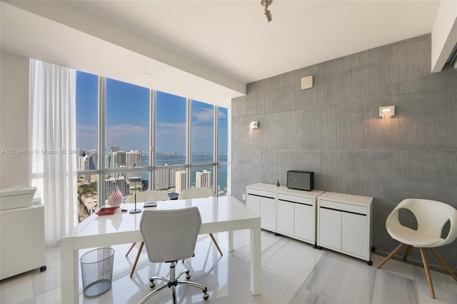 office space with floor to ceiling windows, a water view, light tile flooring, and tile walls