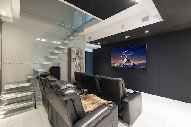 home theater featuring a tray ceiling and light tile flooring