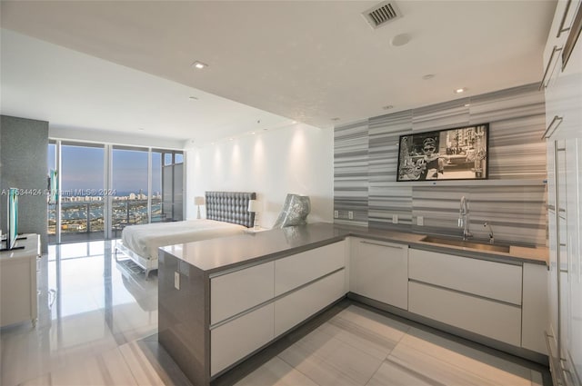 kitchen featuring white cabinets, expansive windows, light tile flooring, and sink