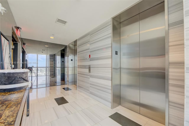 interior space featuring a wall of windows, vanity, tile floors, and elevator