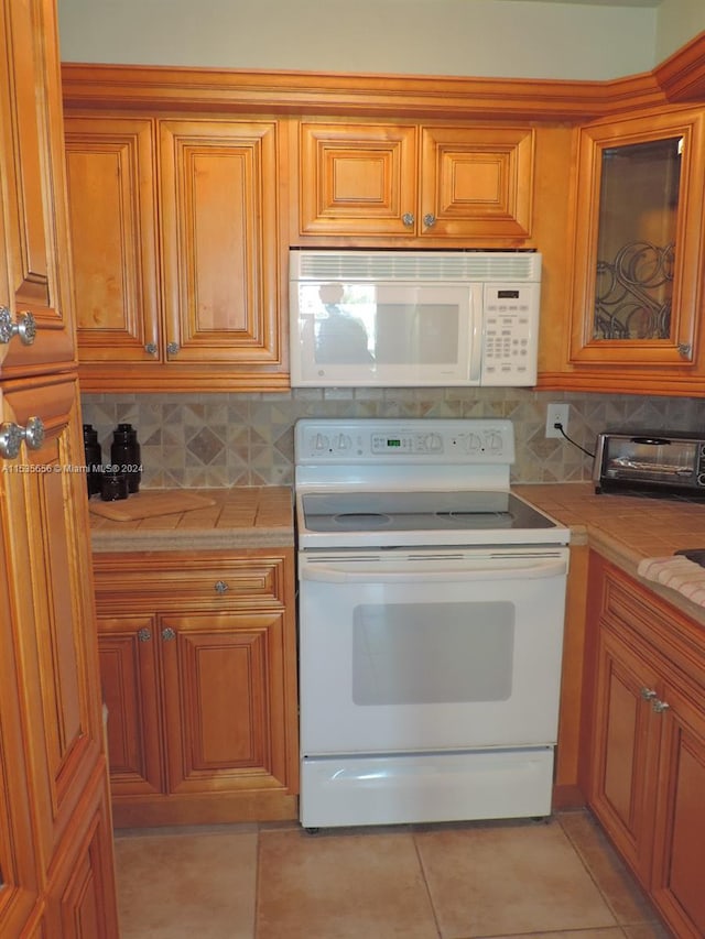 kitchen with white appliances, tile counters, tasteful backsplash, and light tile floors