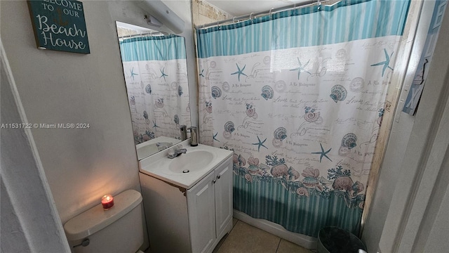 bathroom with tile flooring, vanity with extensive cabinet space, and toilet