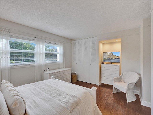 bedroom with dark hardwood / wood-style flooring, a textured ceiling, and a closet