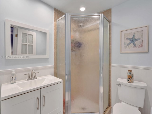 bathroom featuring vanity, toilet, and a shower with shower door