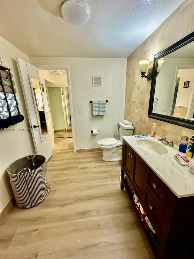 bathroom featuring tile walls, hardwood / wood-style flooring, toilet, and oversized vanity