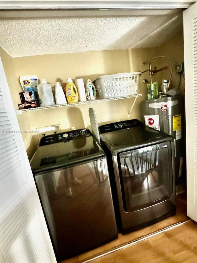 laundry area with washer and clothes dryer, a textured ceiling, and water heater