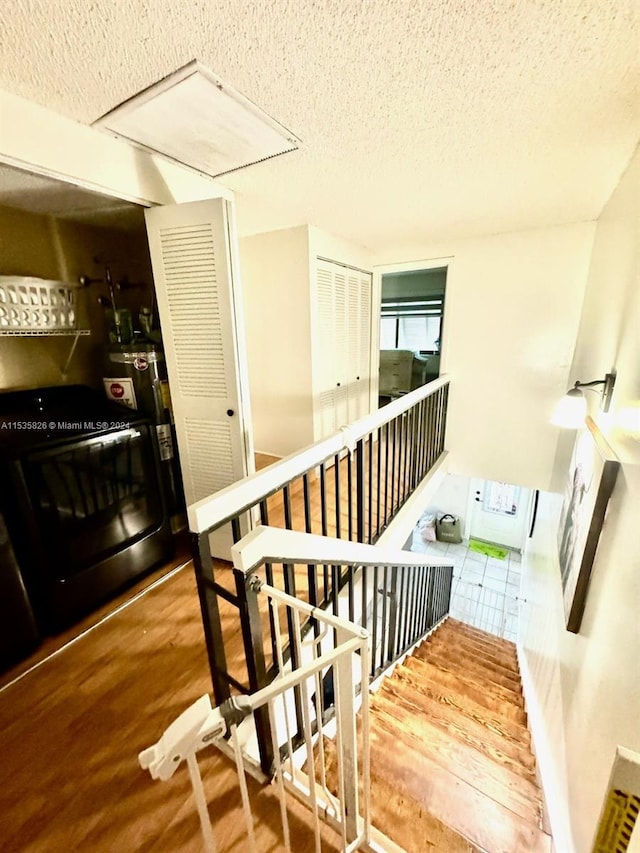 staircase with hardwood / wood-style floors and a textured ceiling