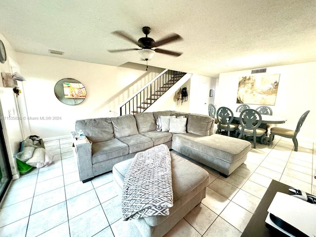 living room with tile flooring, ceiling fan, and a textured ceiling