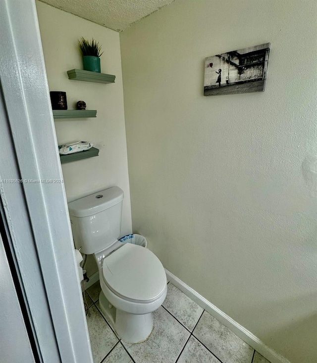 bathroom with tile floors, a textured ceiling, and toilet