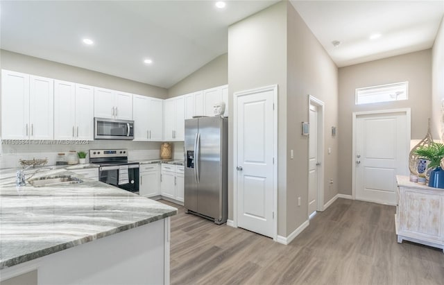 kitchen featuring backsplash, light hardwood / wood-style flooring, stainless steel appliances, white cabinets, and light stone counters