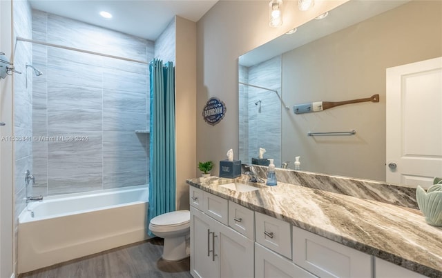 full bathroom with oversized vanity, tiled shower / bath, toilet, and wood-type flooring