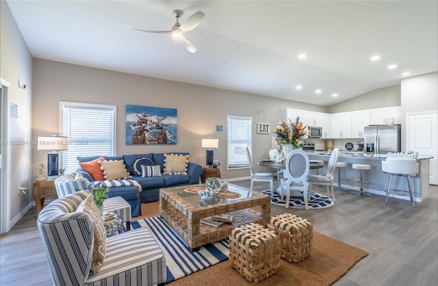 living room featuring light hardwood / wood-style floors, ceiling fan, vaulted ceiling, and a wealth of natural light