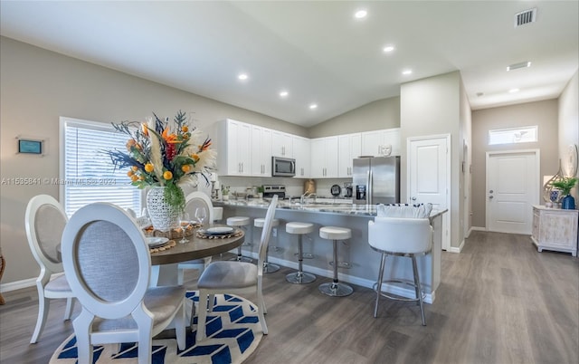 kitchen featuring light hardwood / wood-style floors, stainless steel appliances, white cabinets, and lofted ceiling