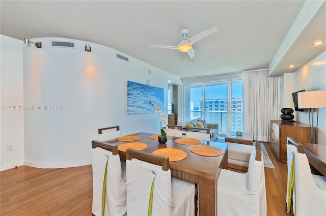 dining area with light hardwood / wood-style floors, ceiling fan, and a wall of windows