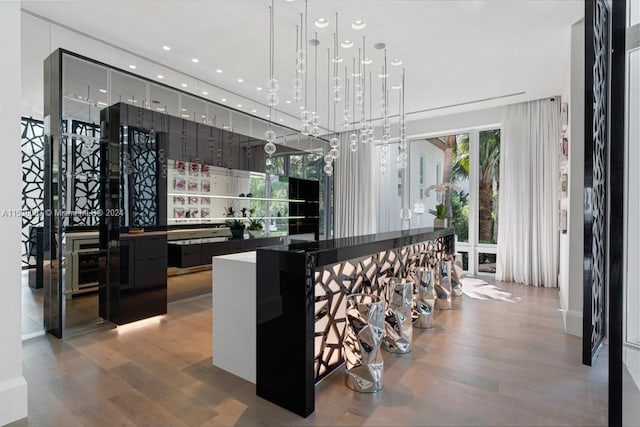 bar with wood-type flooring, pendant lighting, and a notable chandelier