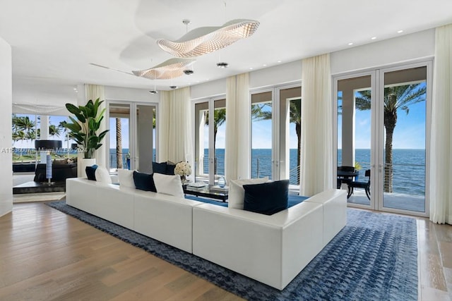 living room with french doors, light hardwood / wood-style floors, and a water view