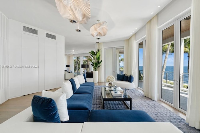 living room featuring light hardwood / wood-style flooring, a water view, and french doors