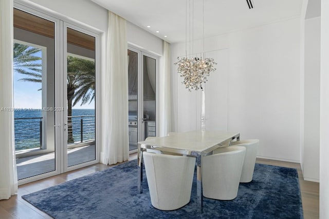 dining room featuring french doors, a water view, and light wood-type flooring