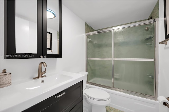 full bathroom featuring combined bath / shower with glass door, vanity, and toilet