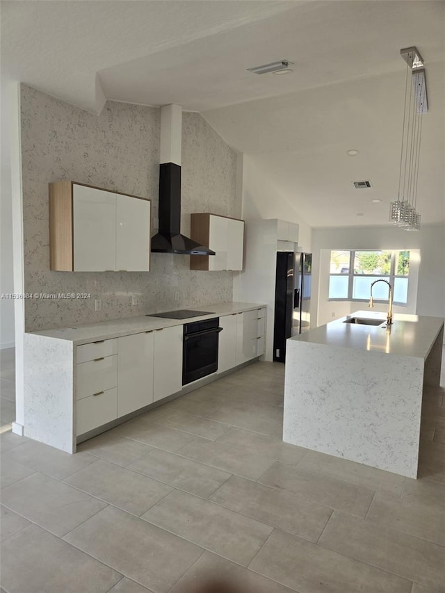 kitchen with white cabinets, lofted ceiling, sink, a center island with sink, and black appliances