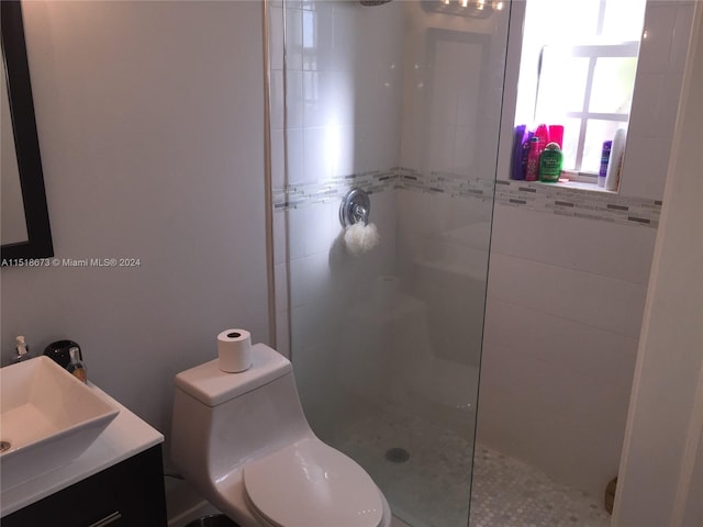 bathroom featuring toilet, vanity, and tiled shower