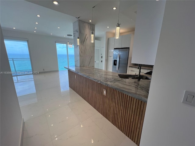 kitchen featuring hanging light fixtures, sink, a water view, light tile floors, and stainless steel refrigerator with ice dispenser