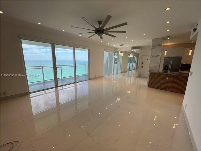 unfurnished room featuring light tile floors, ceiling fan, and a water view