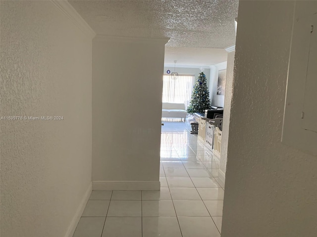 hallway featuring crown molding, light tile floors, and a textured ceiling