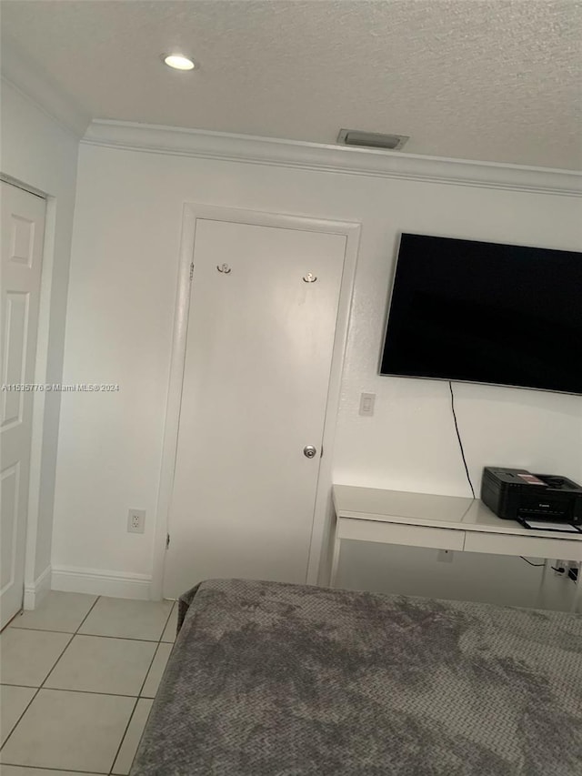 interior space featuring ornamental molding, a textured ceiling, and light tile floors