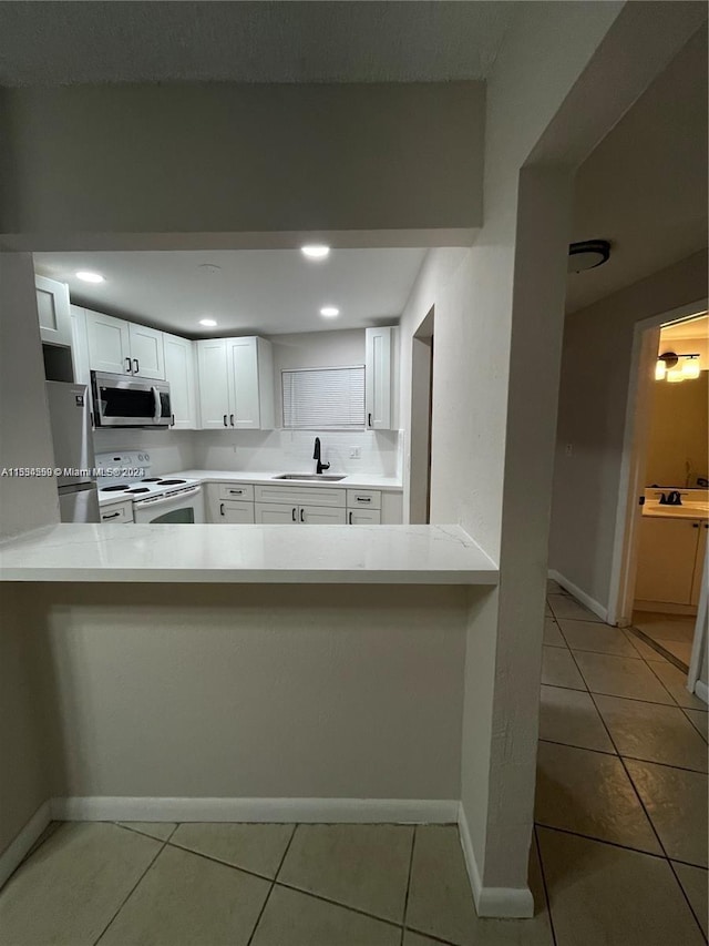 kitchen with tile flooring, white cabinetry, stainless steel appliances, and sink