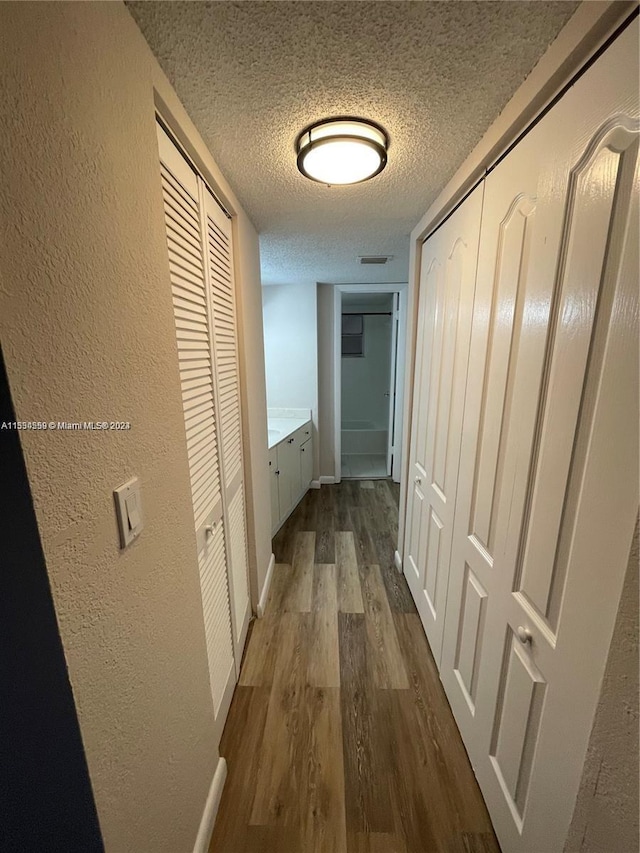 hall with a textured ceiling and hardwood / wood-style flooring