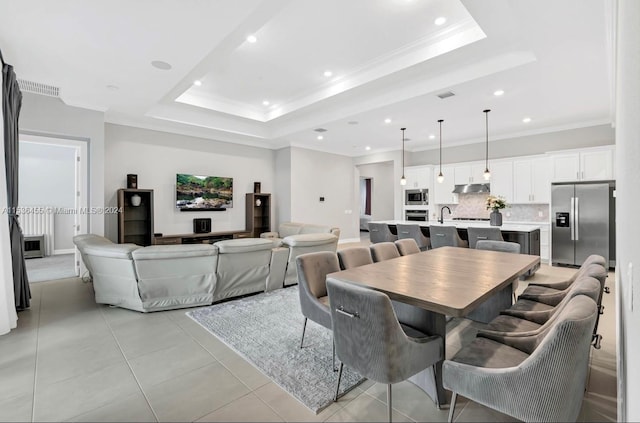 tiled dining room featuring a raised ceiling, ornamental molding, and sink