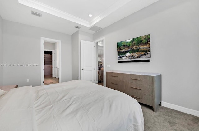 bedroom featuring ensuite bath, light colored carpet, and a tray ceiling