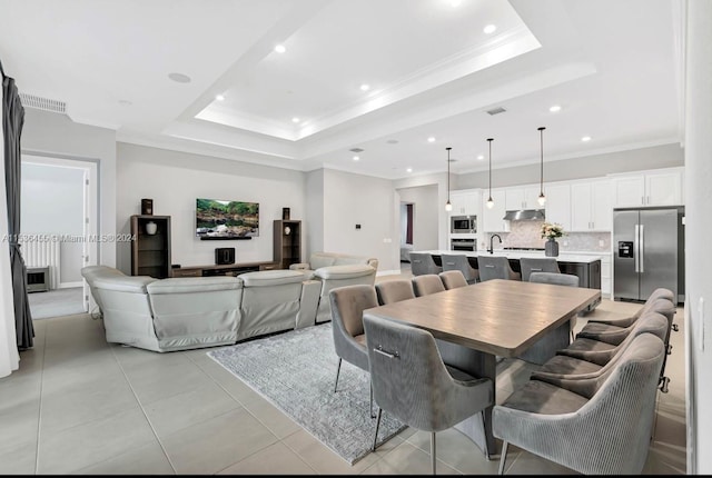 tiled dining space with crown molding, a raised ceiling, and sink