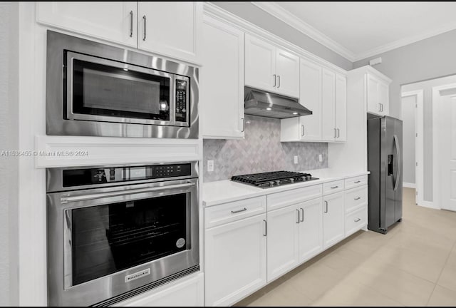 kitchen featuring ornamental molding, stainless steel appliances, light tile flooring, tasteful backsplash, and white cabinetry