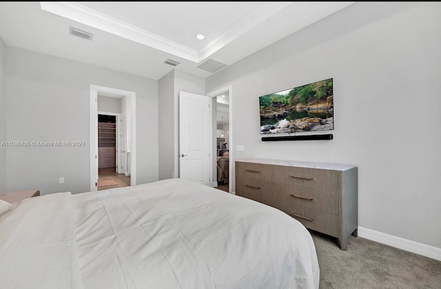 bedroom featuring light carpet, a tray ceiling, and connected bathroom