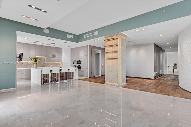 interior space featuring a center island, backsplash, light tile flooring, and gray cabinetry